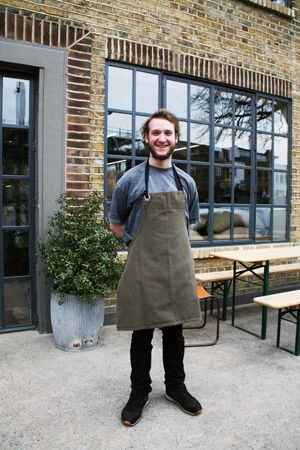 Barista Felix wearing one of Field Grey’s aprons